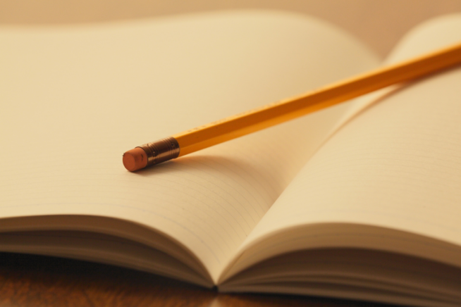 Pencil laying on an open blank notebook