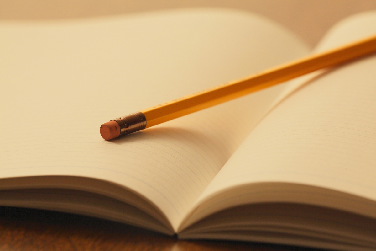 Pencil laying on an open blank notebook